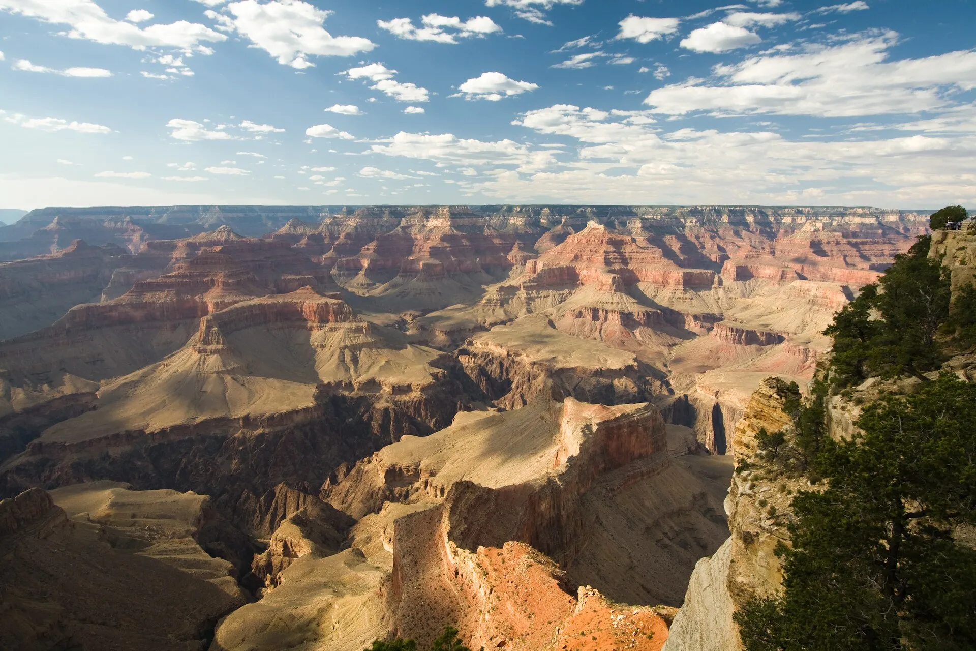 A very wide view of the Grand Canyon, an enormous rocky valley with red and orange cliffs stretching as far as you can see.